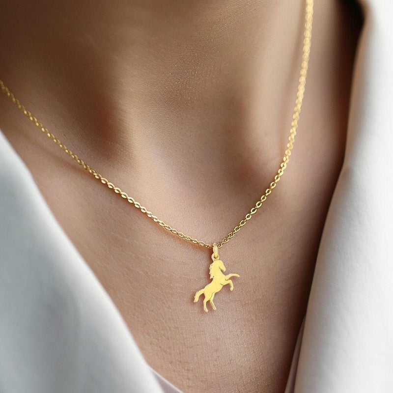Fine gold chain necklace with a small running horse pendant on a plain background (5 of 12)
