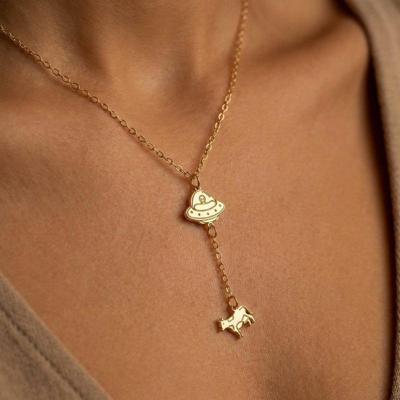 Gold UFO pendant beaming up a tiny cow, hung on a fine cable chain
