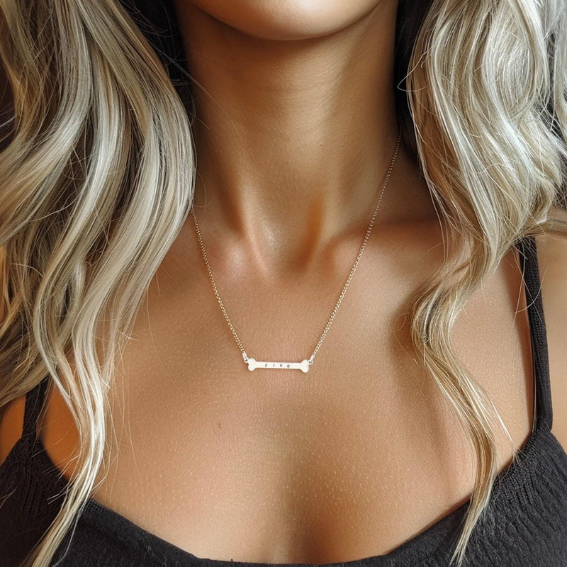 Small gold dog bone pendant on a fine chain, shown against a plain backdrop. (3 of 7)