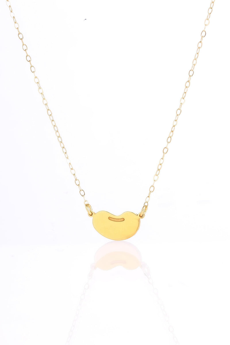 Tiny gold bean pendant on a delicate cable chain against a white background.