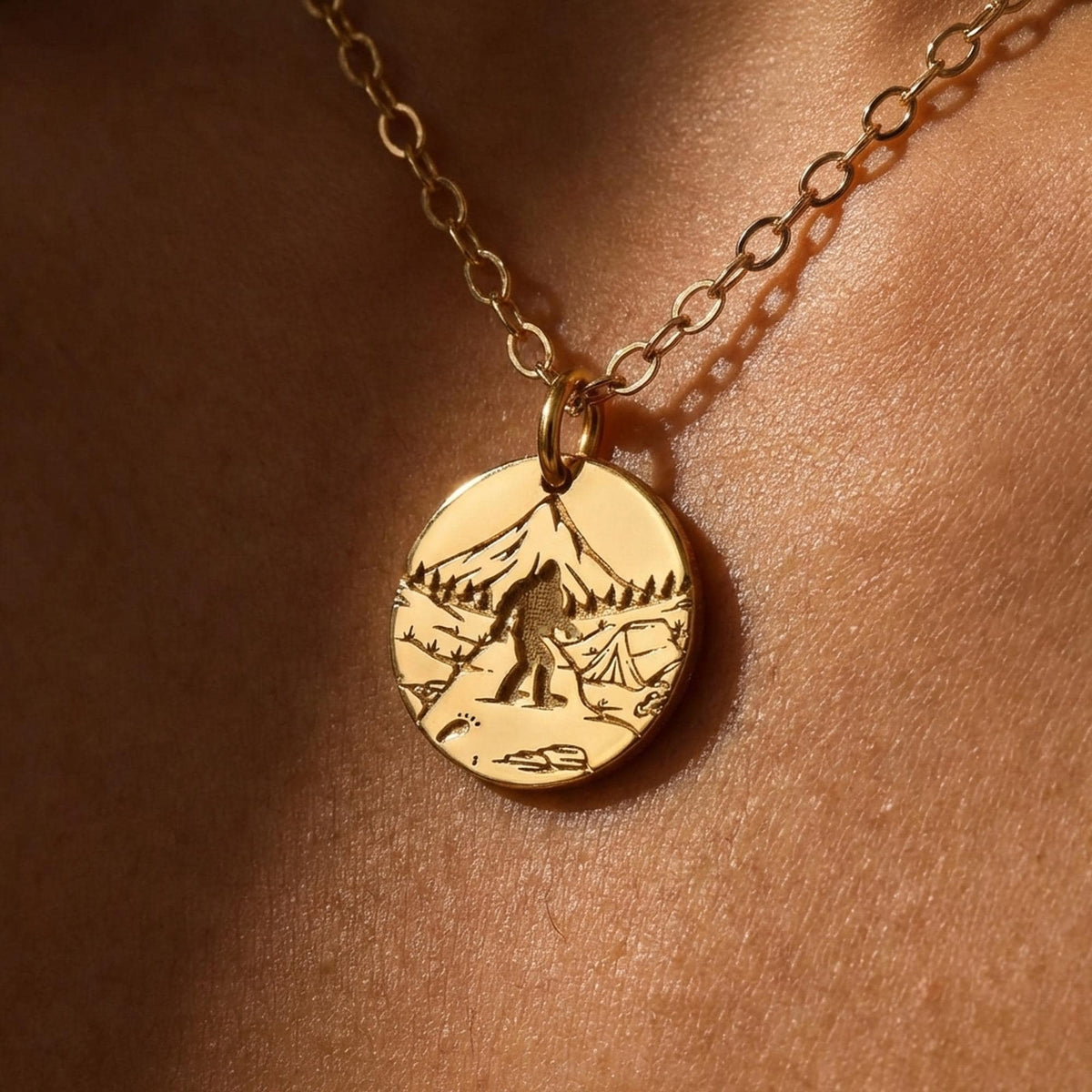 Round gold Bigfoot medallion pendant on a fine chain, shown on a white background.