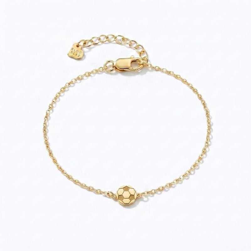 Fine gold chain bracelet with a small soccer ball charm and extender on a wrist