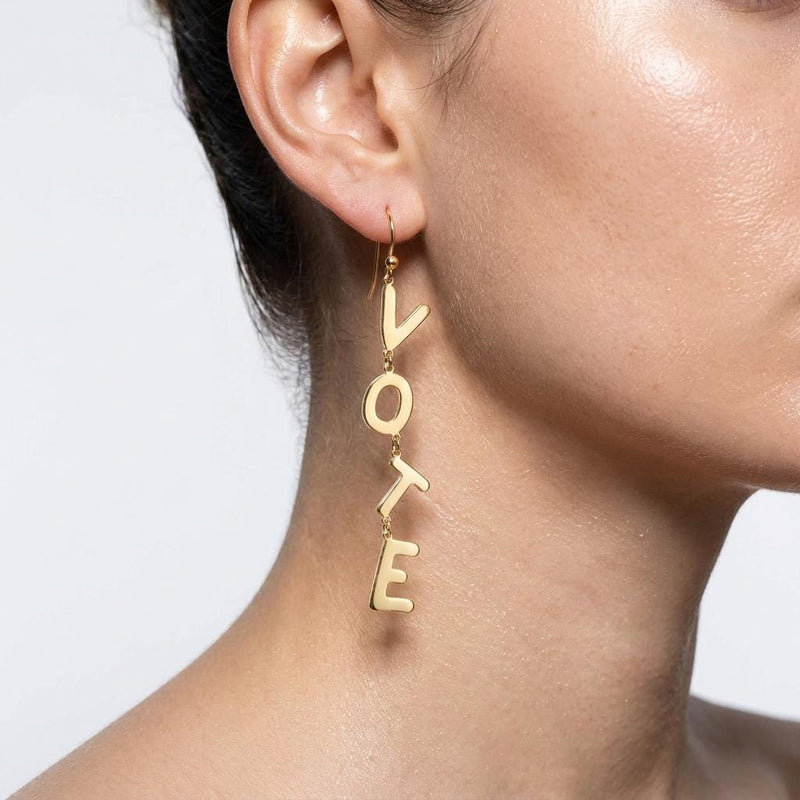 Pair of long gold earrings spelling the word VOTE in cut out letters