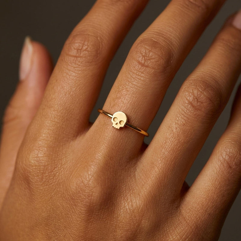 Dainty gold skull ring, small flat skull on a thin round band, worn on a hand