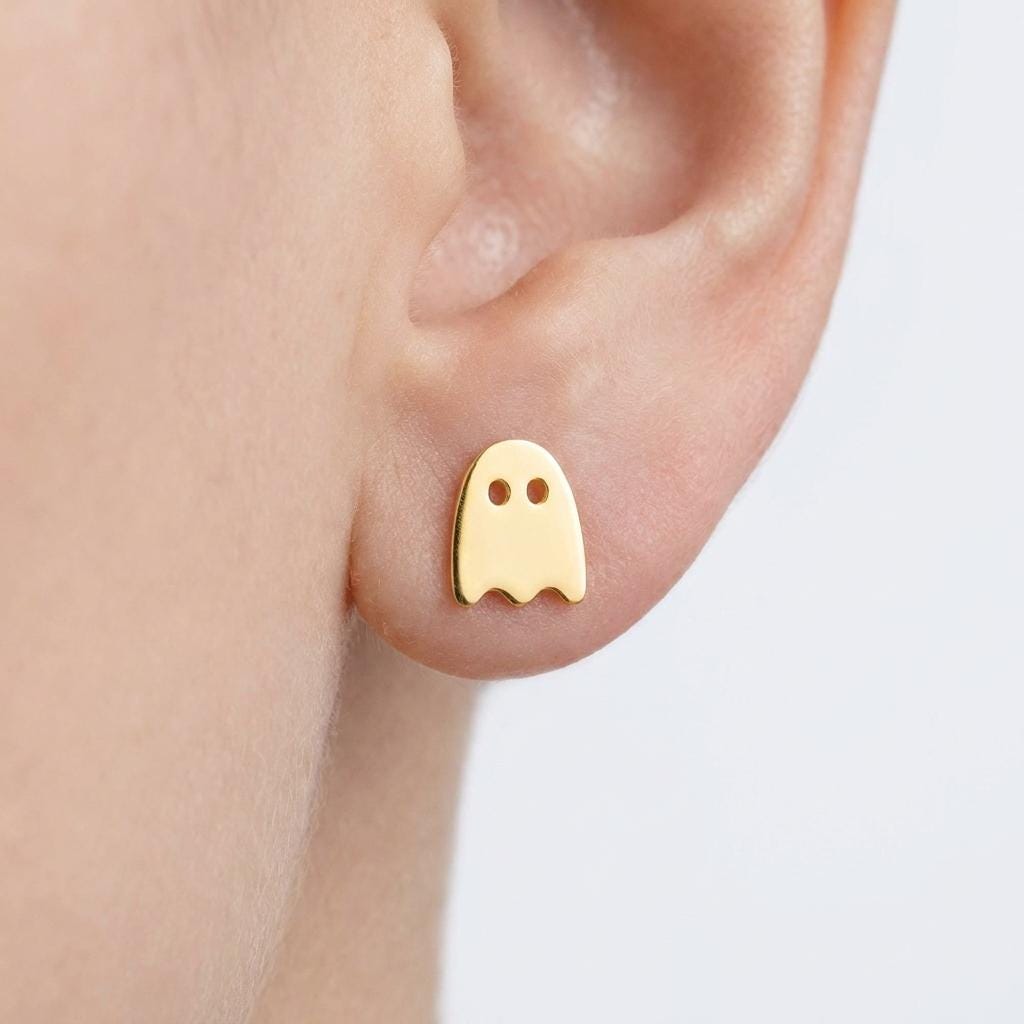 Small gold ghost stud earrings with two dot eyes and a wavy hem