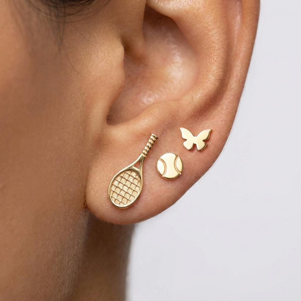 Mismatched stud earrings: a tiny gold tennis ball on one side, a tennis racket on the other (2 of 9)