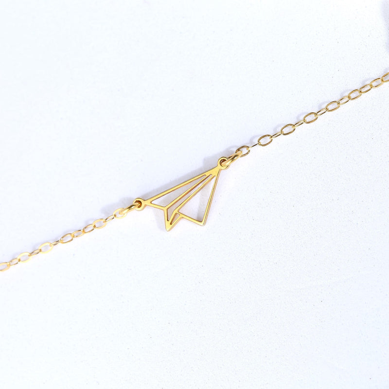 Gold folded paper airplane charm necklace on a fine cable chain