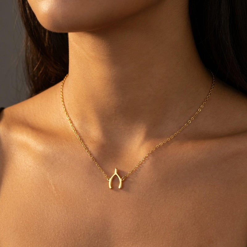 Small gold wishbone pendant hanging from a fine cable chain