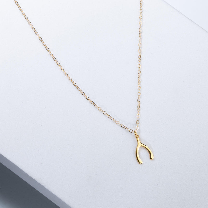 Small gold wishbone pendant hanging from a fine cable chain (5 of 12)