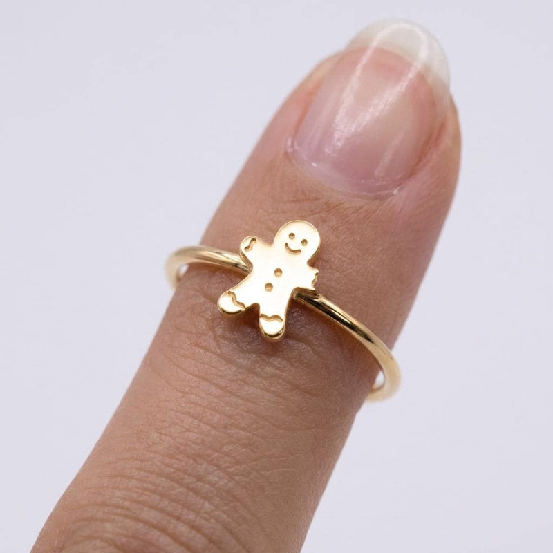 Gold ring with a small smiling gingerbread man charm on a thin band