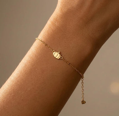 Thin gold chain bracelet with a small ribbed pumpkin charm and stem