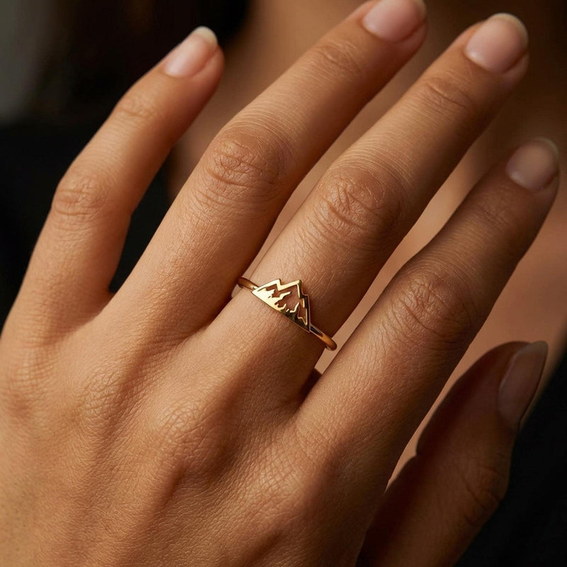 Thin gold stacking ring with a small flat mountain peak across the top, on a hand (2 of 9)