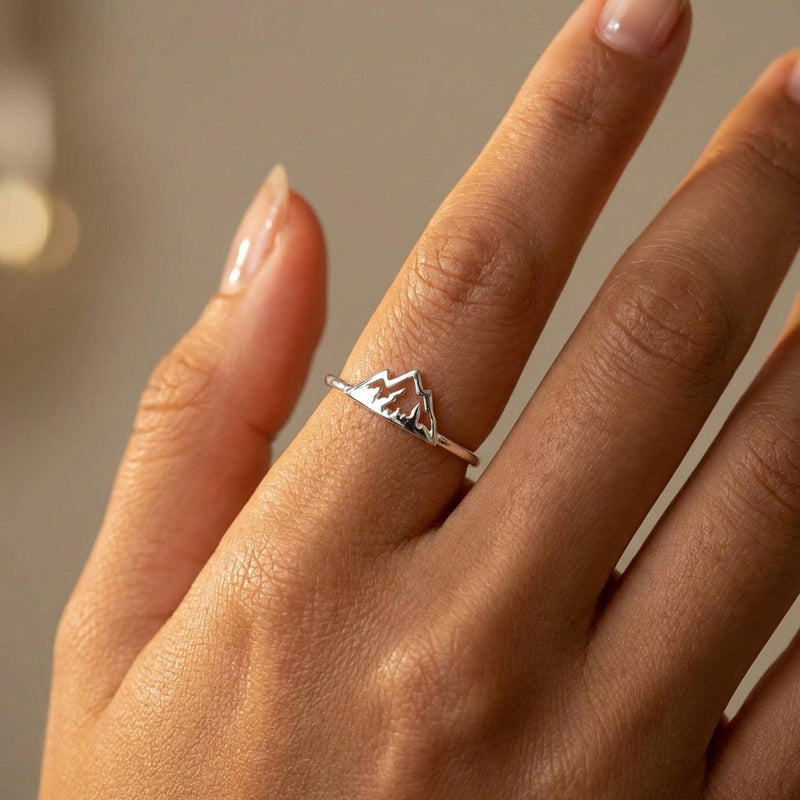 Thin gold stacking ring with a small flat mountain peak across the top, on a hand (3 of 9)