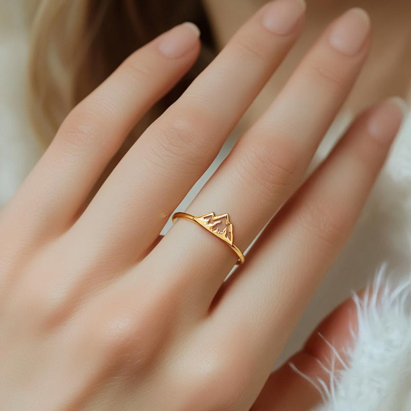 Thin gold stacking ring with a small flat mountain peak across the top, on a hand (9 of 9)