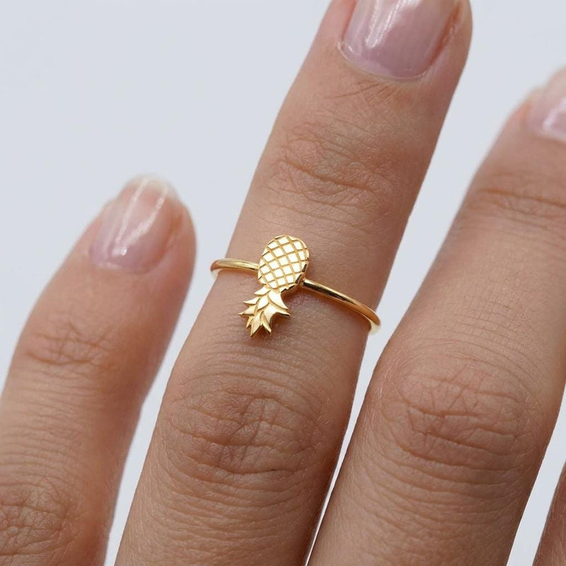 Thin gold ring with a small pineapple sitting on the crown of the band.