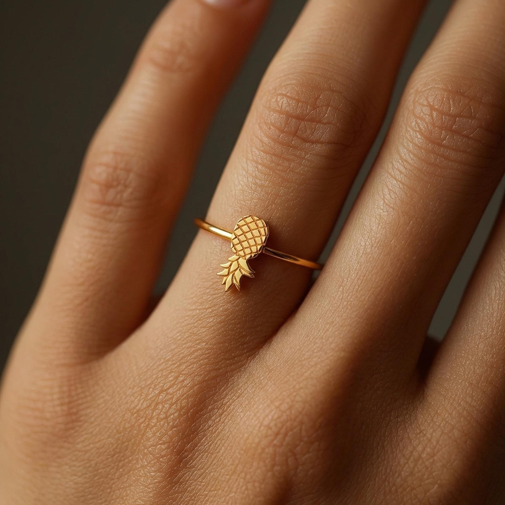 Thin gold ring with a small pineapple sitting on the crown of the band. (2 of 8)