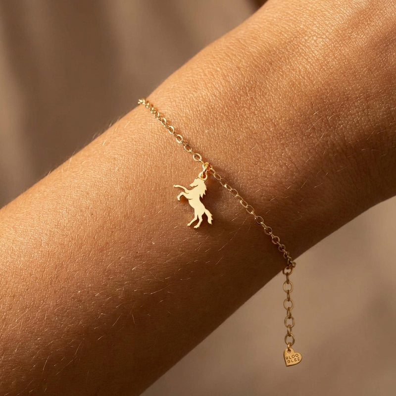 Fine gold chain bracelet with a tiny horse charm and lobster clasp on a wrist (2 of 11)