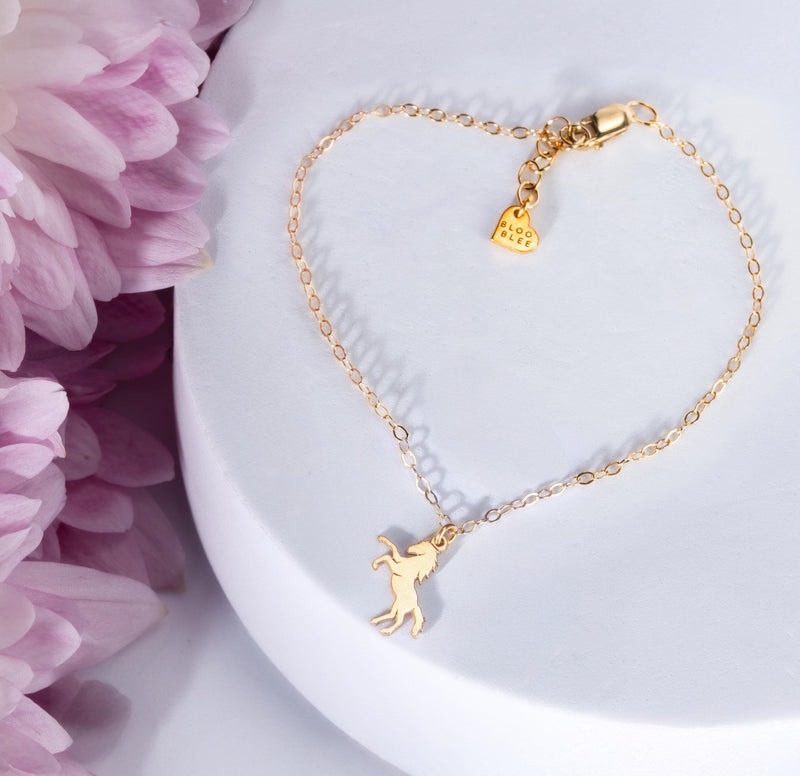 Fine gold chain bracelet with a tiny horse charm and lobster clasp on a wrist (3 of 11)
