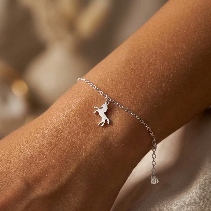 Fine gold chain bracelet with a tiny horse charm and lobster clasp on a wrist (4 of 11)
