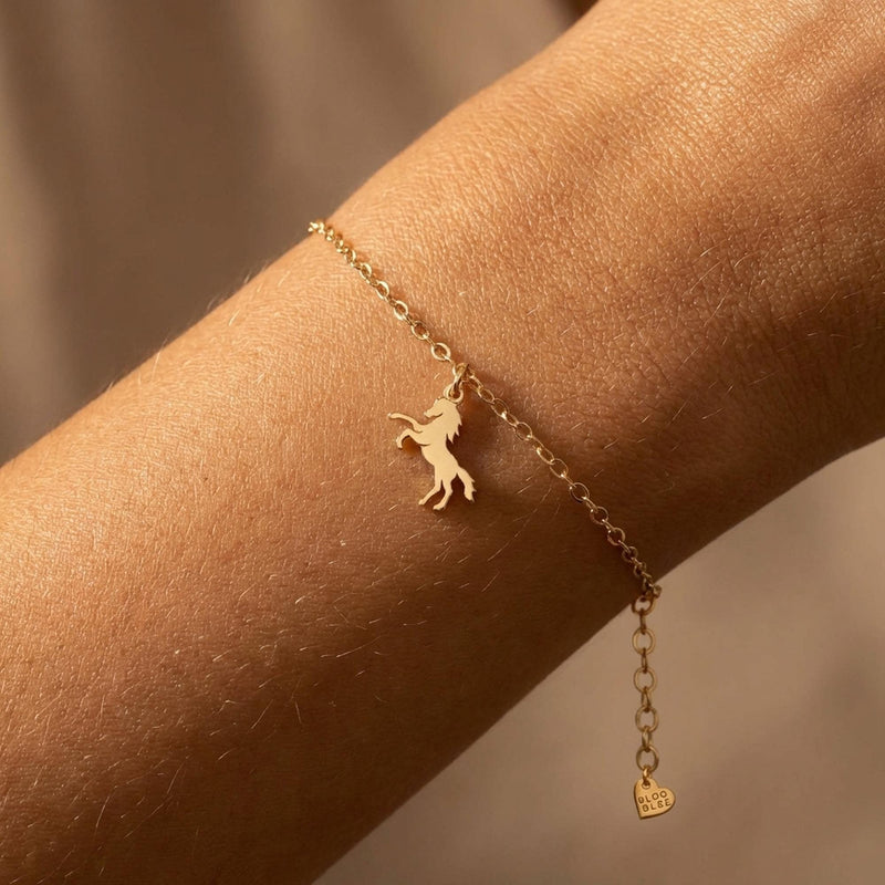 Fine gold chain bracelet with a tiny horse charm and lobster clasp on a wrist (5 of 11)