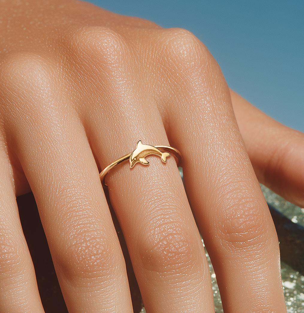 Thin gold ring with a small sculpted dolphin arcing across the top