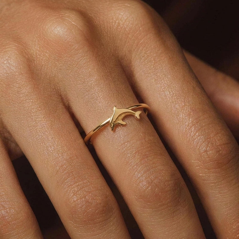 Thin gold ring with a small sculpted dolphin arcing across the top (7 of 9)