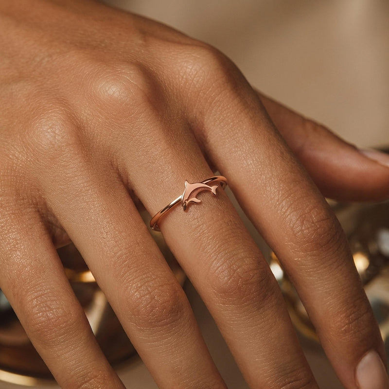 Thin gold ring with a small sculpted dolphin arcing across the top (8 of 9)