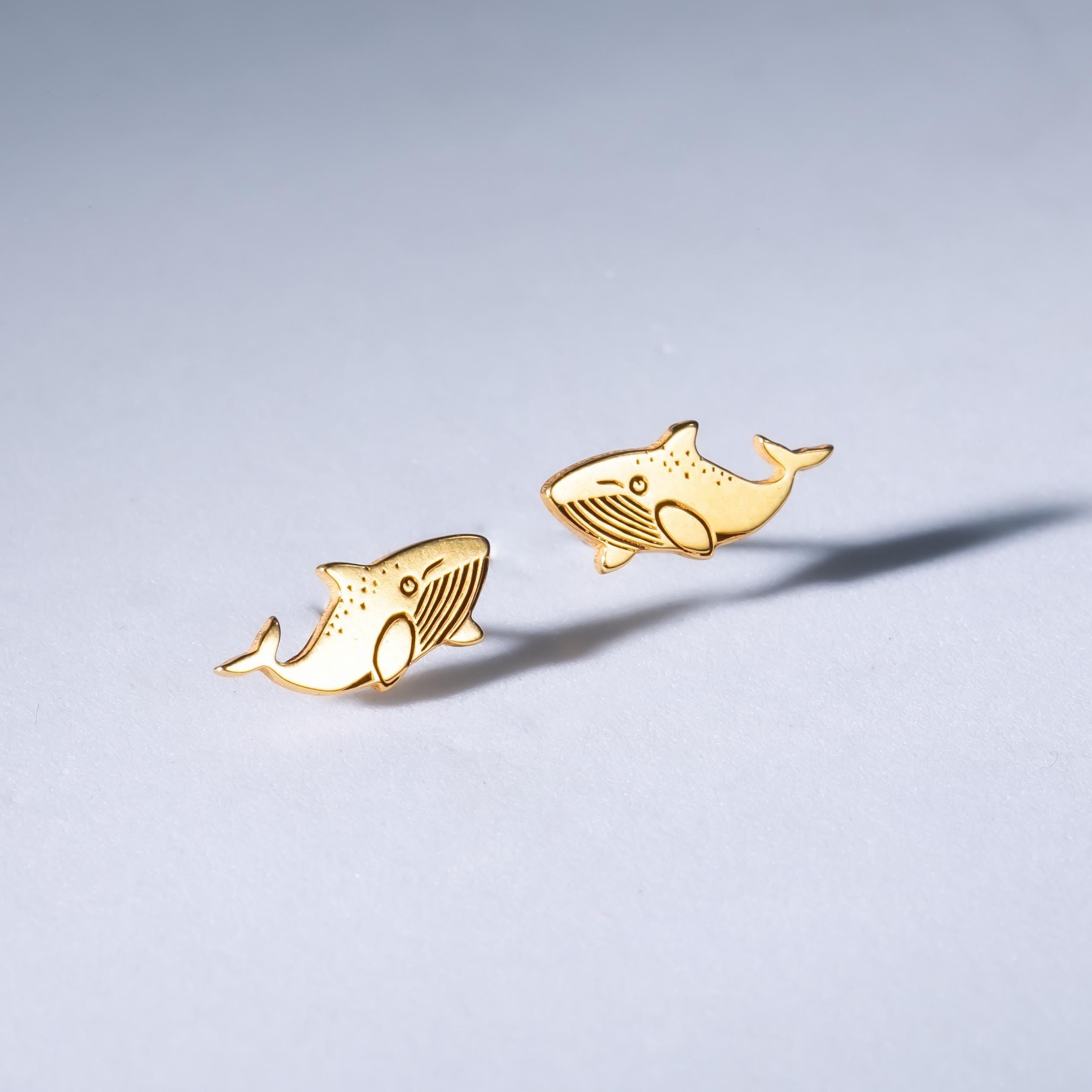 Pair of small gold whale stud earrings shown flat on a white background. (2 of 10)
