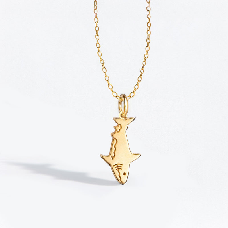 Fine gold chain necklace with a small shark pendant shown in profile