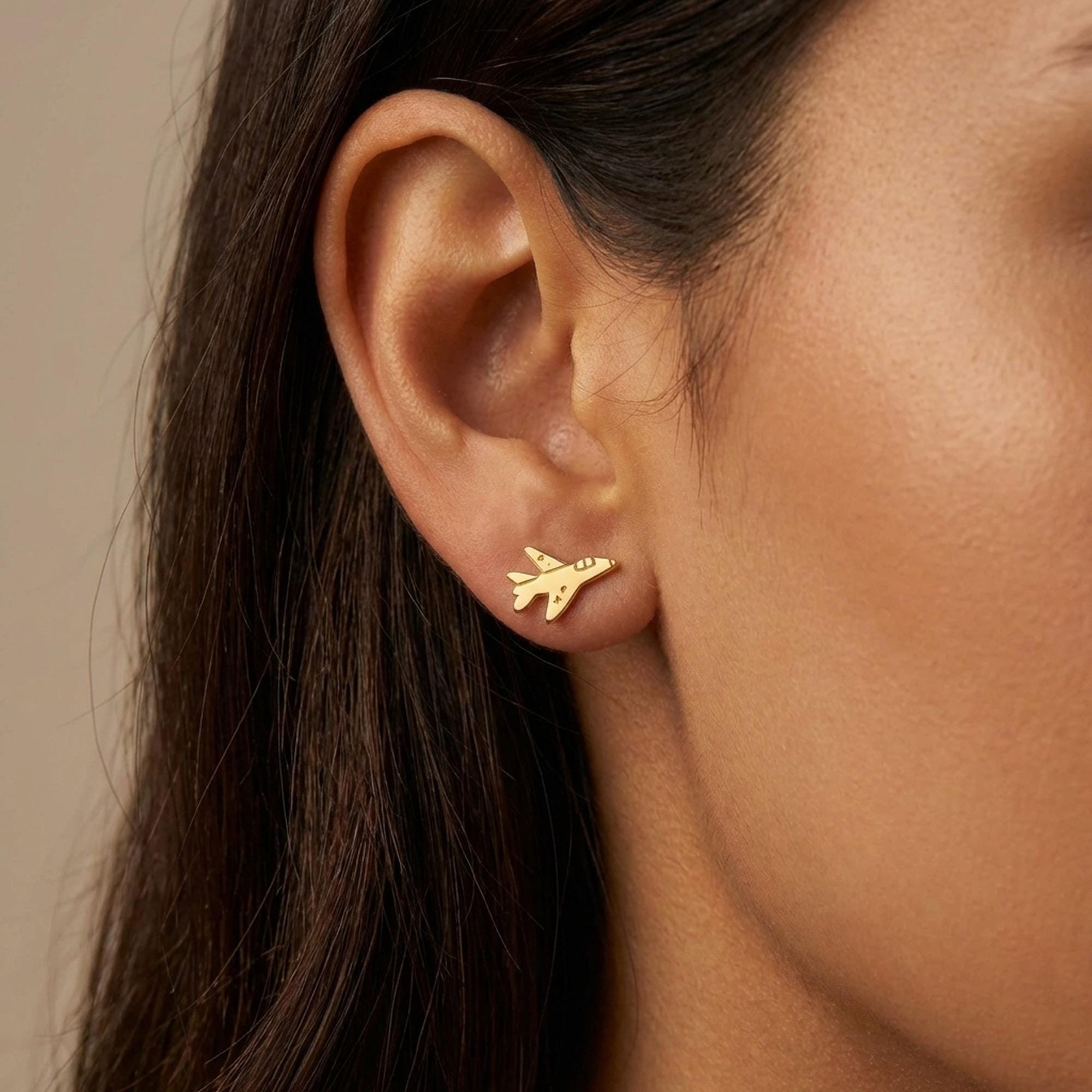 Pair of small gold fighter jet stud earrings with swept wings on a white background (2 of 13)