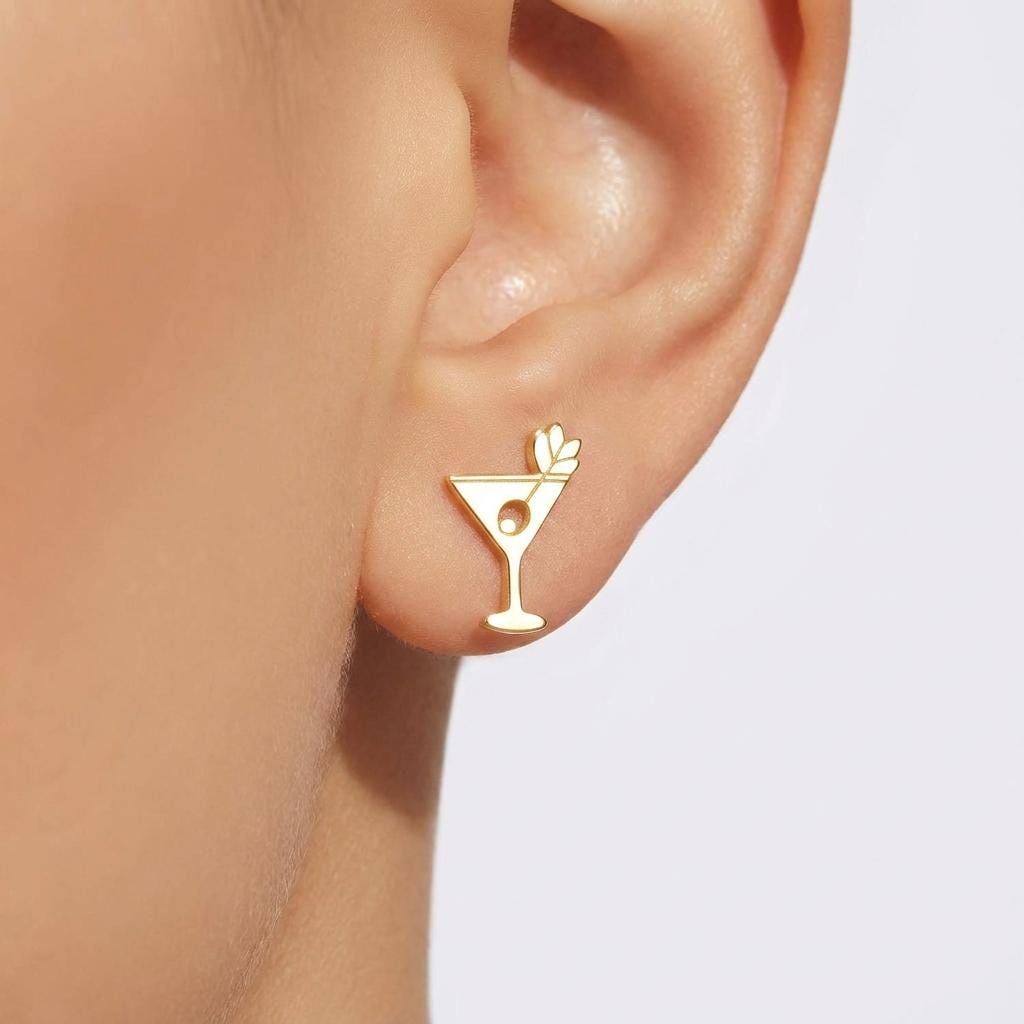 Small gold martini glass stud earrings with an olive on a pick, shown as a pair