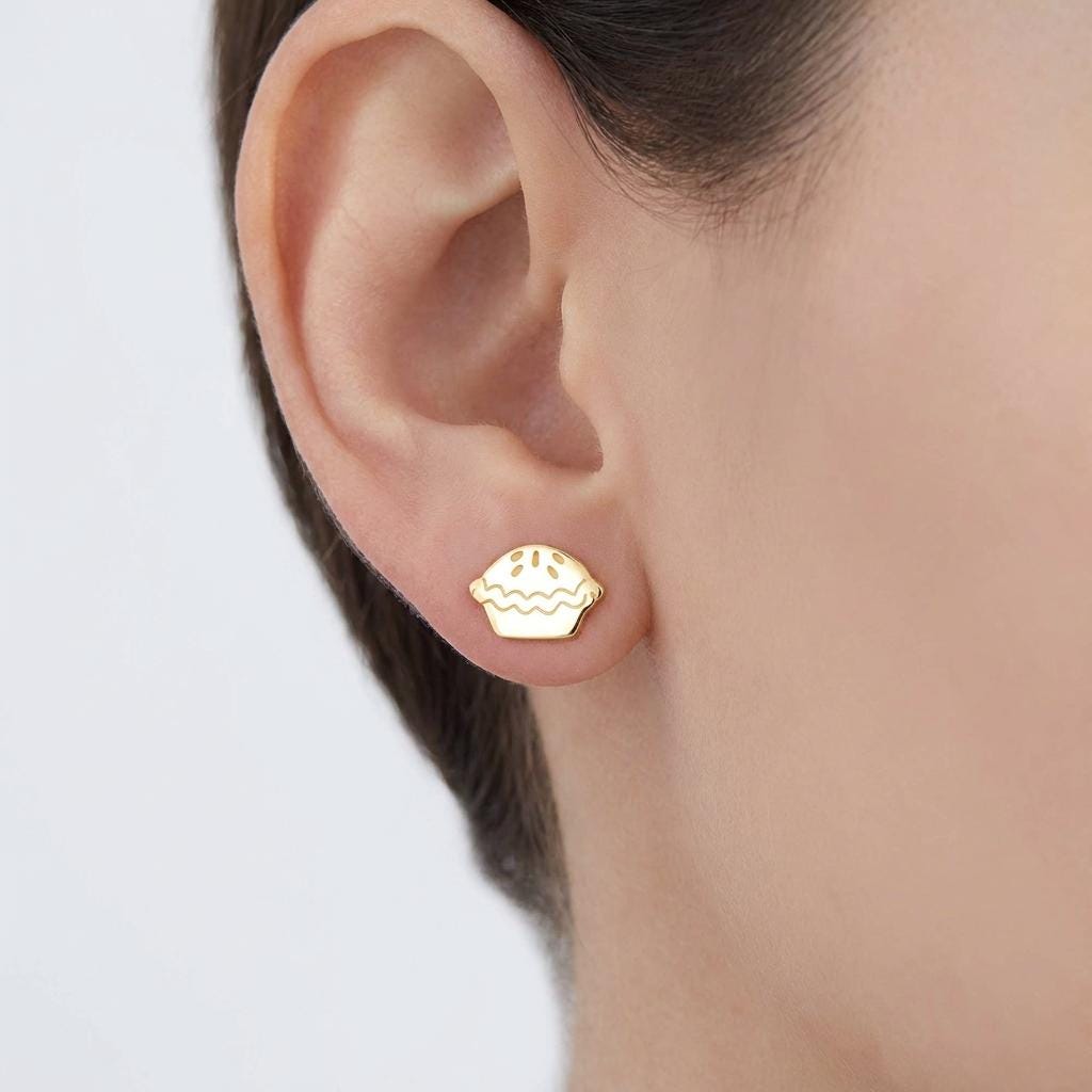 Pair of tiny gold pie slice stud earrings with lattice crust, white background.