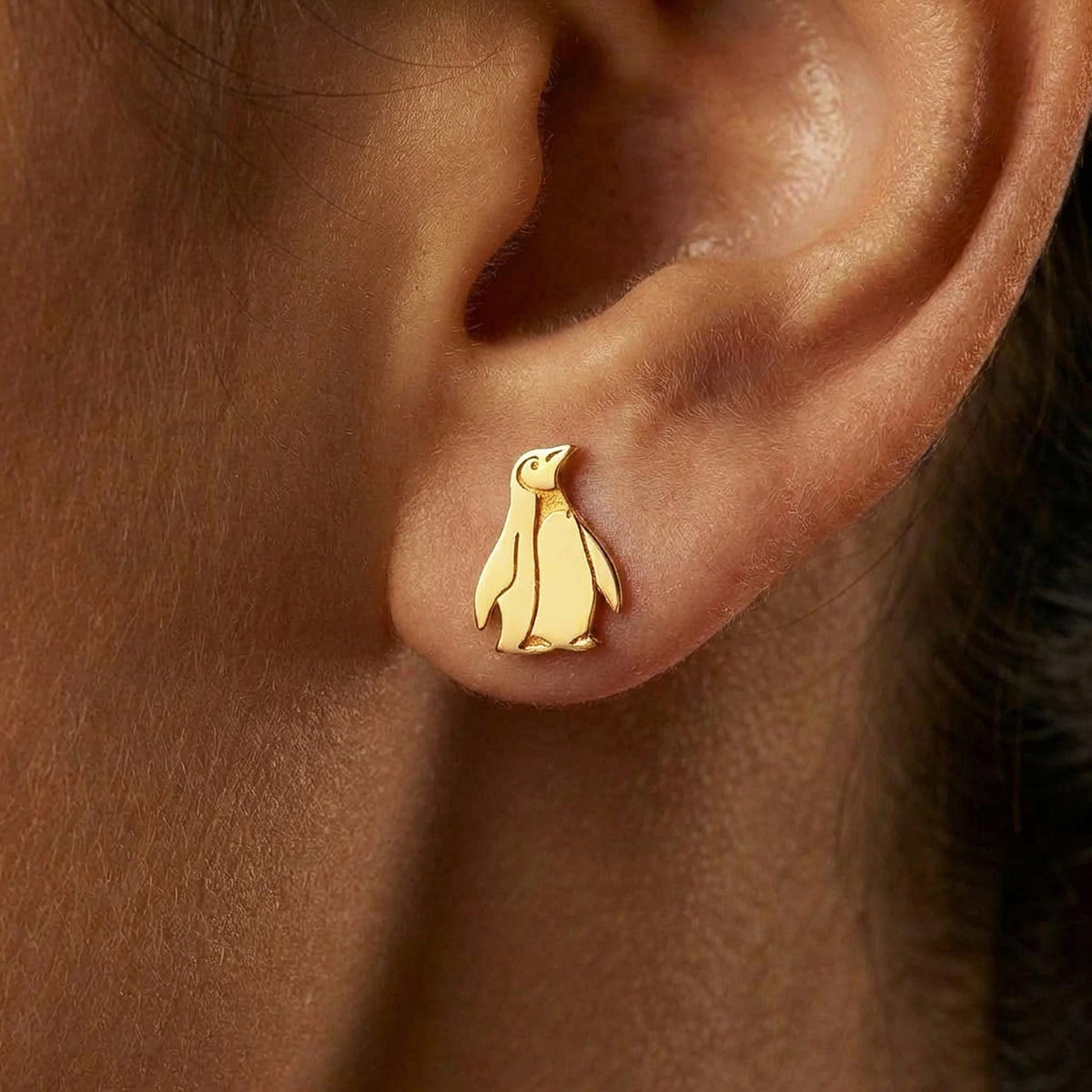 Pair of small gold penguin stud earrings with short flippers and a belly panel.
