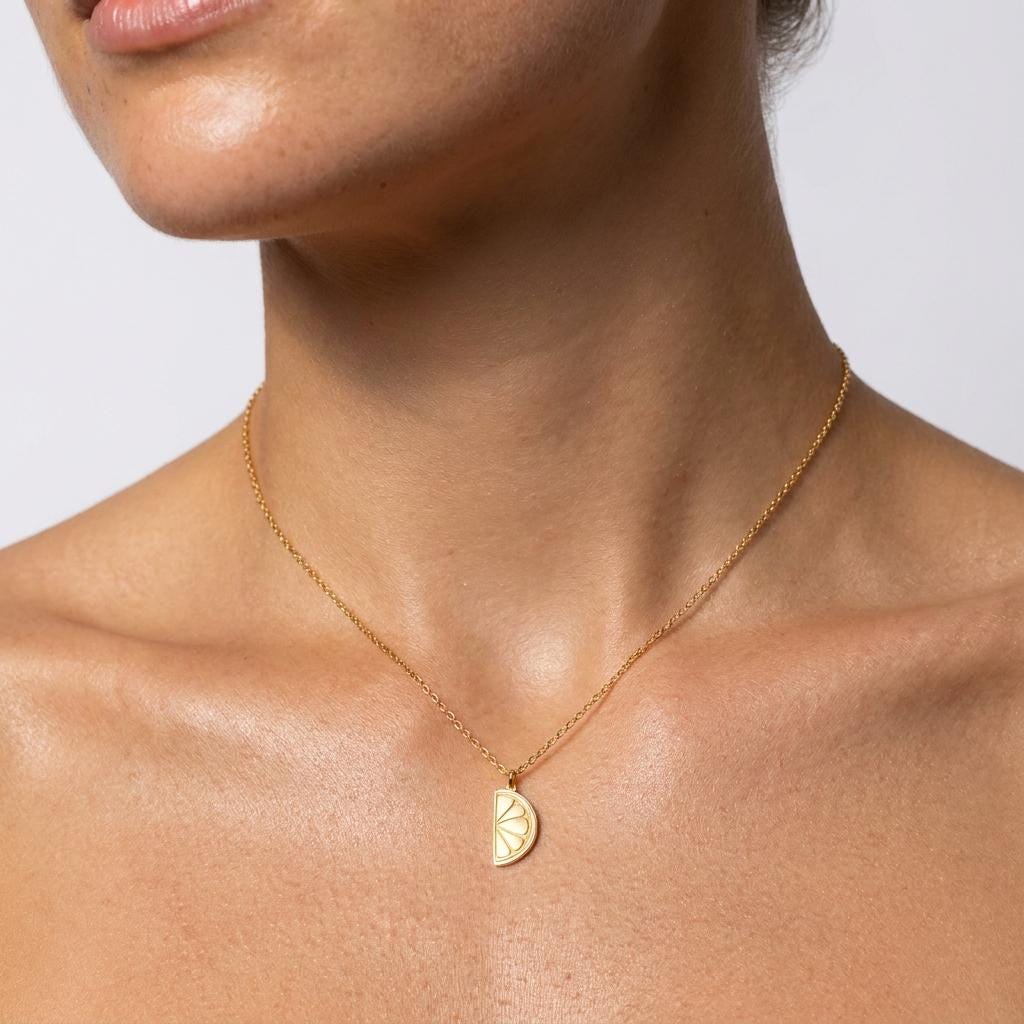 Round gold lemon slice pendant with wedge detail, on a fine chain