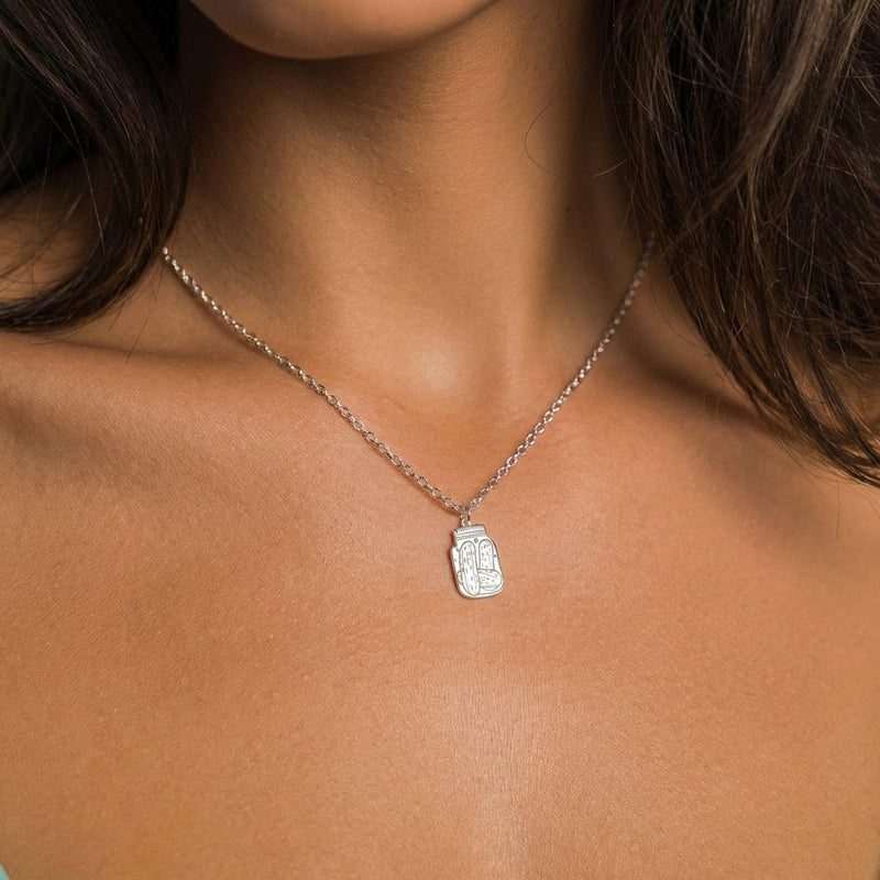 Fine gold chain necklace with a small pickle jar pendant on a plain background (3 of 8)