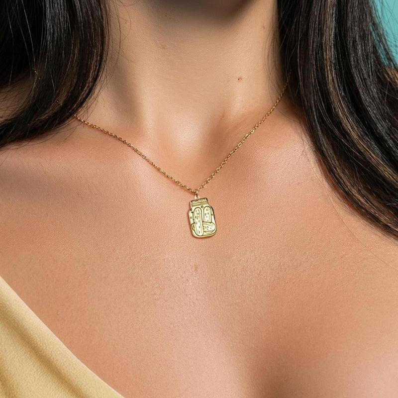 Fine gold chain necklace with a small pickle jar pendant on a plain background (4 of 8)