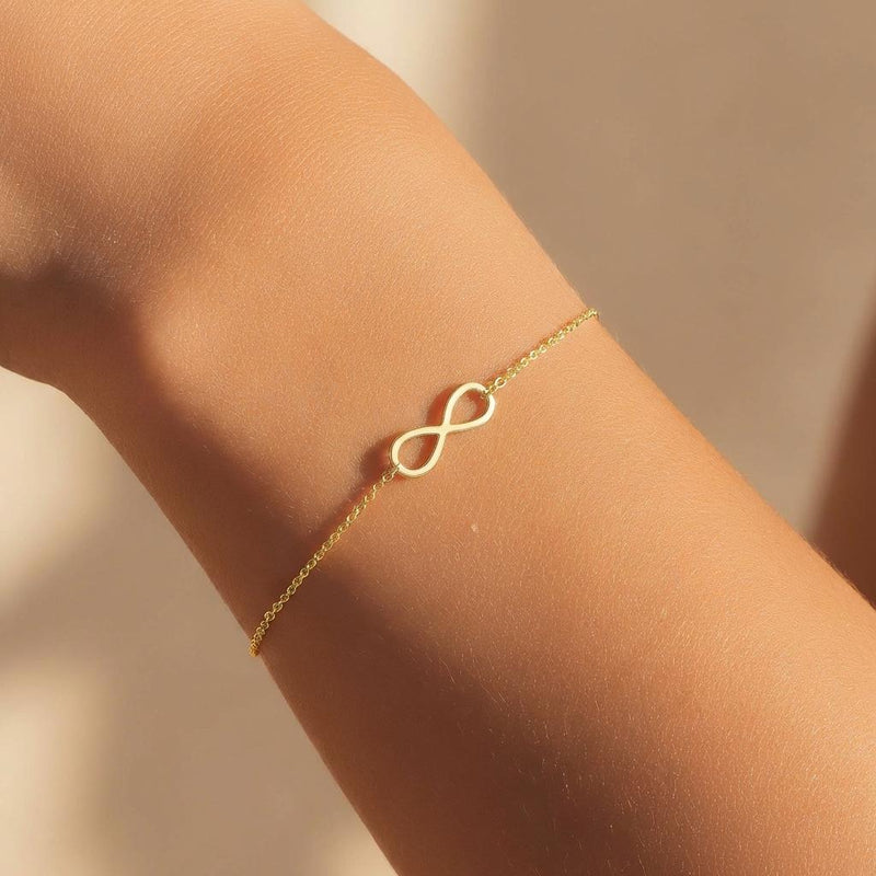 Fine chain bracelet with a small flat gold infinity loop charm at the center. (2 of 6)