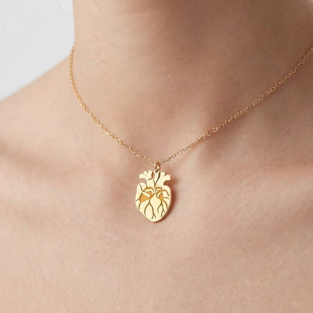 Very small anatomical heart pendant in gold on a short fine chain worn high on the neck
