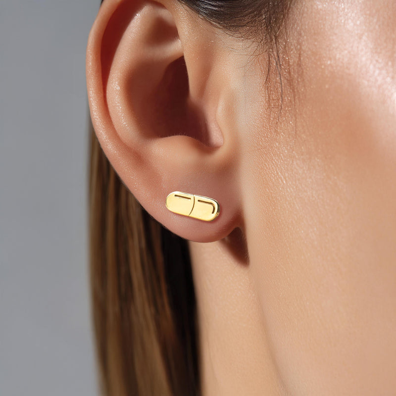 Pair of narrow gold capsule pill stud earrings with a seam across the middle