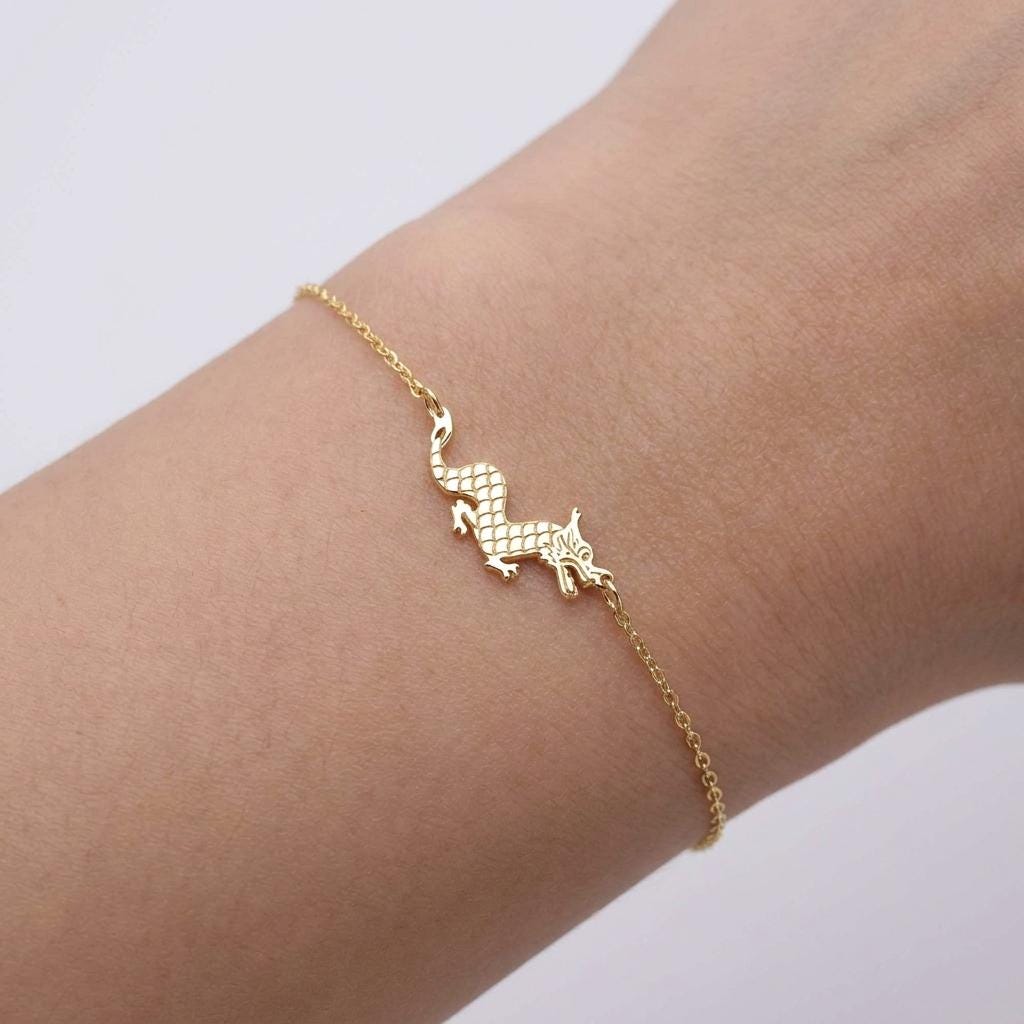 Fine gold chain bracelet with a small dragon charm in profile
