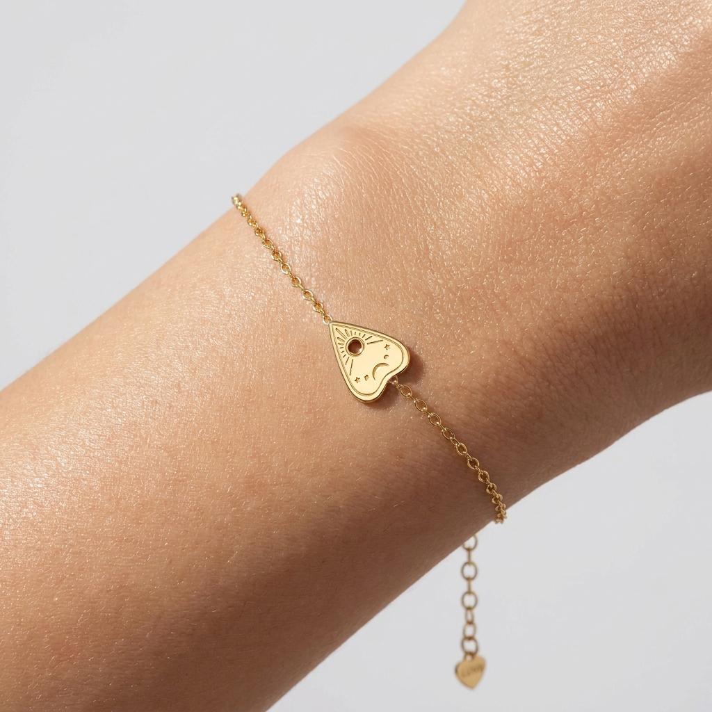 Fine gold bracelet with a heart shaped planchette charm and cut out window.