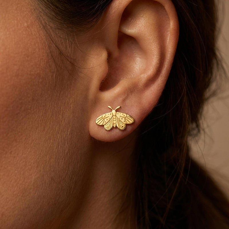 Small gold moth stud earrings with broad wings and feathered antennae