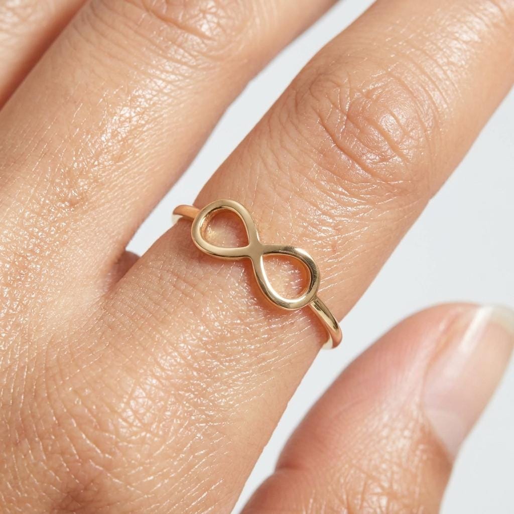 Thin gold infinity ring with a flat crossed loop on the band