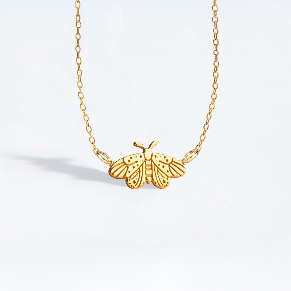 Fine gold chain necklace with a small moth pendant with open wings and antennae