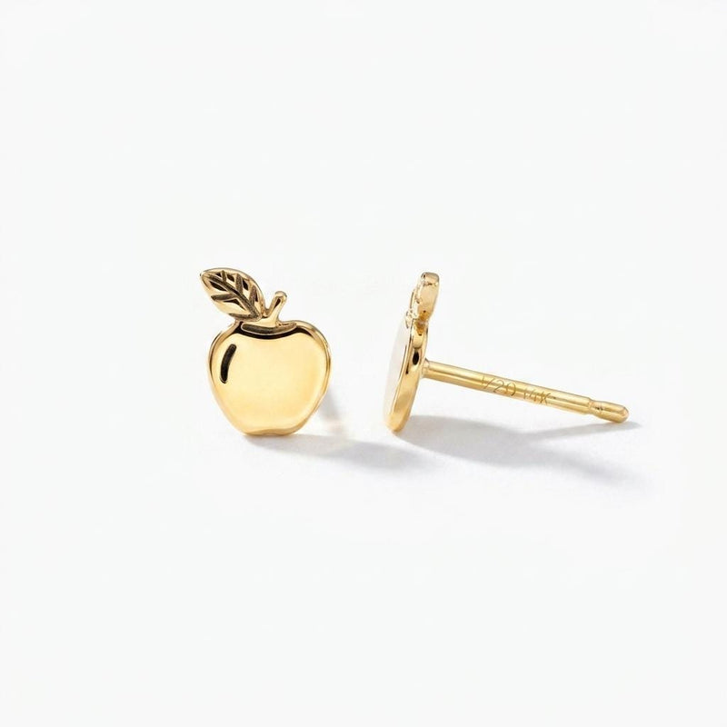 Pair of tiny gold apple stud earrings with stem and leaf, shown on white