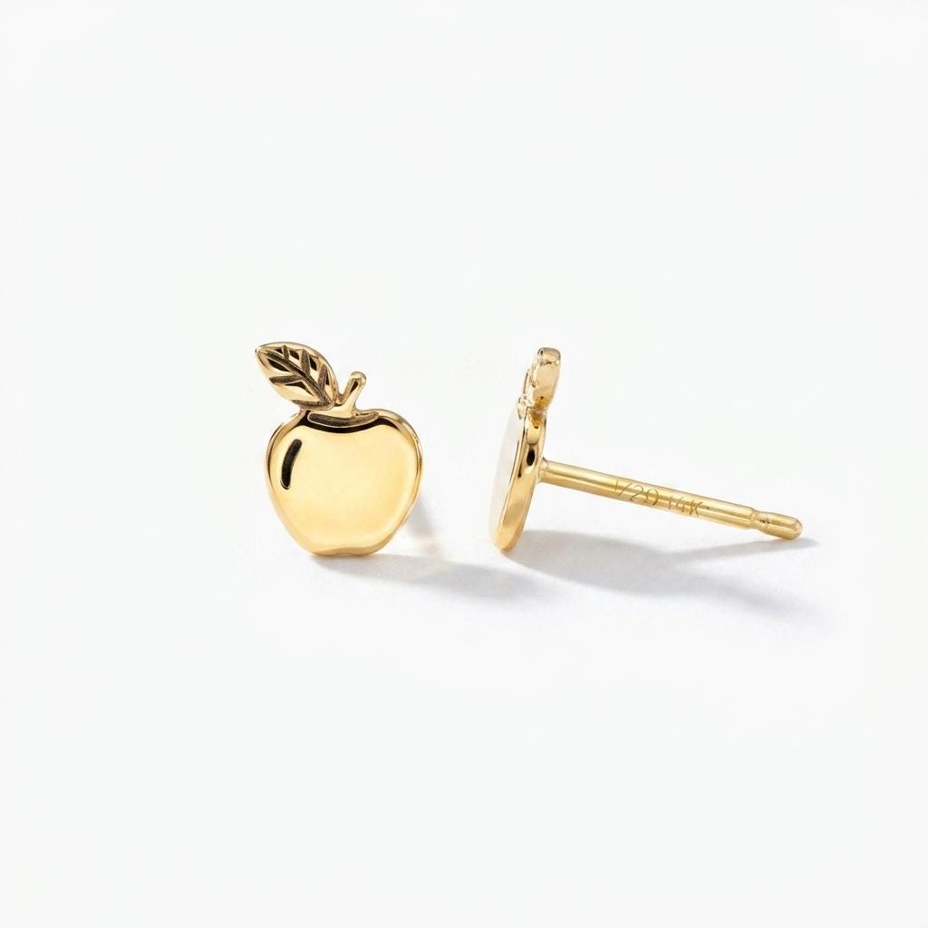 Pair of tiny gold apple stud earrings with stem and leaf, shown on white