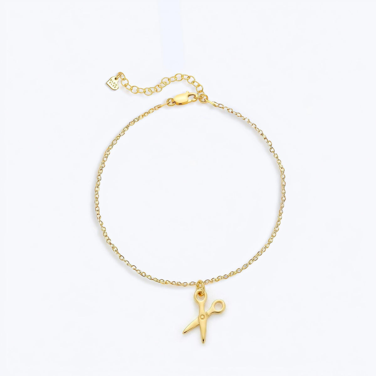 Tiny gold scissors charm on a fine chain bracelet with lobster clasp