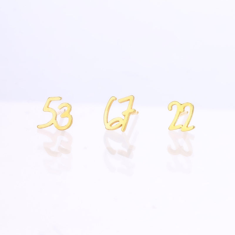 Pair of gold number stud earrings, one reading six and one reading seven