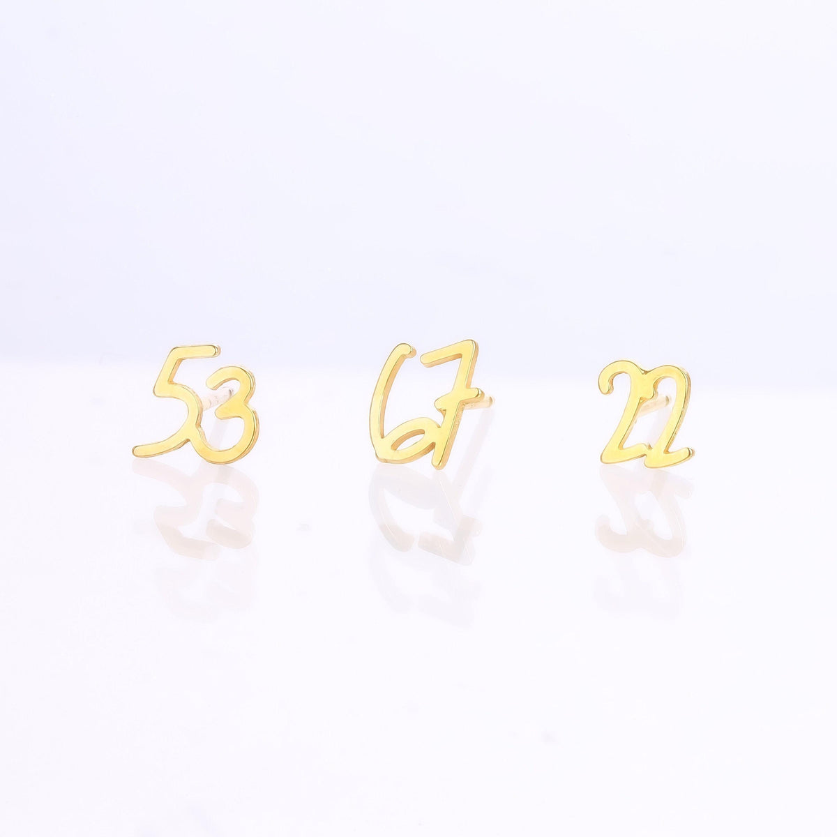 Pair of gold number stud earrings, one reading six and one reading seven