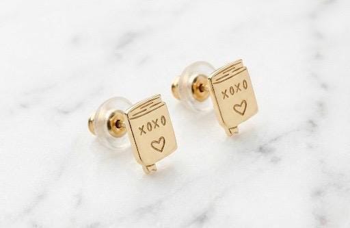 Pair of small gold XOXO letter stud earrings in a handwritten style